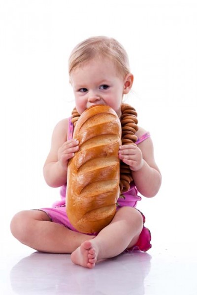 Baby biting a loaf of bread in roll beads isolated on white